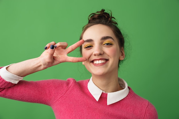 Portrait d'une jeune femme joyeuse debout isolé, geste de paix