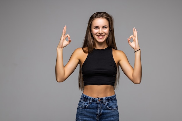 Portrait d'une jeune femme joyeuse montrant un signe ok avec des doigts isolés sur fond gris