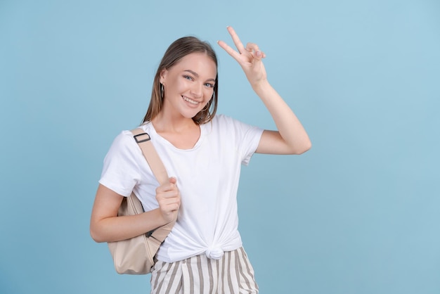 Portrait jeune femme joyeuse en t-shirt blanc avec sac à dos en détournant les yeux