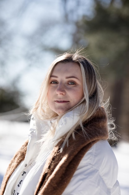 Portrait Une jeune femme joyeuse en vêtements d'hiver chauds s'amusant dans la forêt d'hivers parmi les arbres