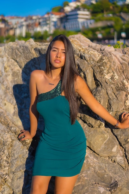 Portrait d'une jeune femme latine profitant de l'été avec une robe verte au bord de la mer