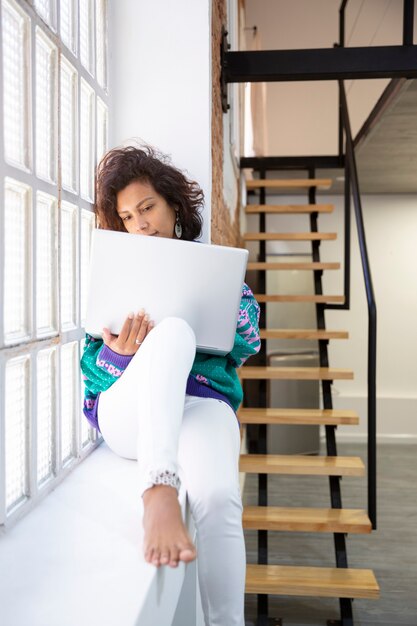 Portrait de jeune femme latine travaillant avec son ordinateur portable à la maison. Espace pour le texte.