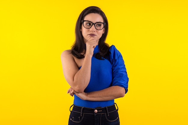 Portrait de jeune femme à lunettes avec chemisier bleu sur fond jaune avec diverses expressions faciales