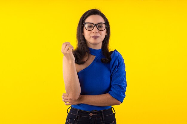 Portrait de jeune femme à lunettes avec chemisier bleu sur fond jaune avec diverses expressions faciales