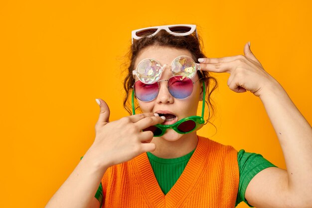 Portrait d'une jeune femme lunettes de soleil multicolores sur le visage posant grimace fond jaune inchangé