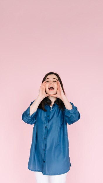 Portrait de jeune femme avec des mains d'expression joyeuse près de la bouche ouverte comme si elle partageait des nouvelles ou racontait