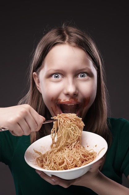 Photo portrait d'une jeune femme mangeant des spaghettis sur un fond noir