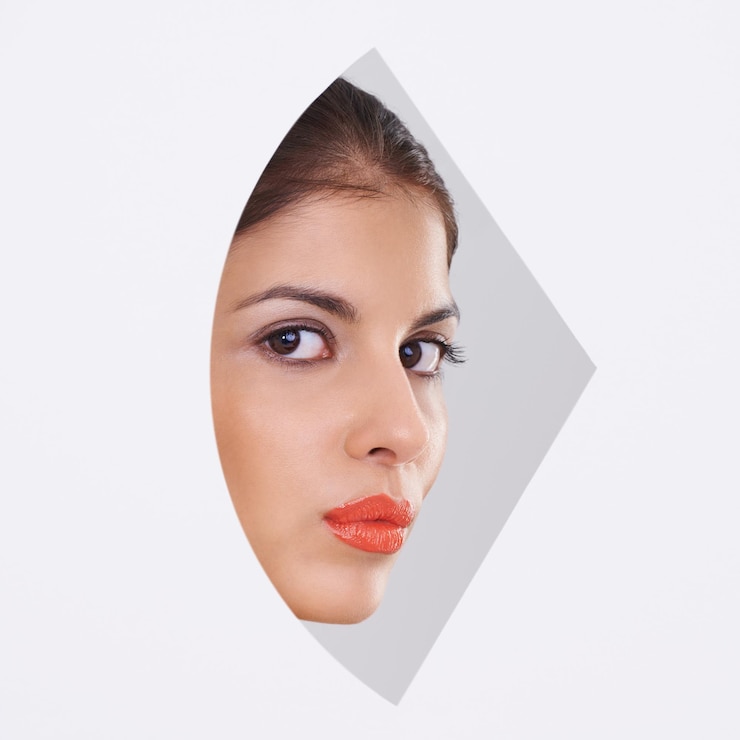 Photo portrait de jeune femme et maquillage dans un découpage et un studio pour les cosmétiques, les soins de la peau et la dermatologie visage du modèle en beauté et en fondation avec un gros plan géométrique et une forme créative sur un fond blanc