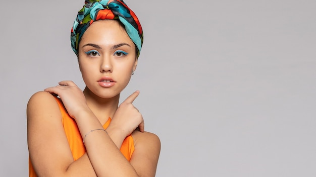 Portrait d'une jeune femme avec un maquillage lumineux et un foulard à la mode. Fond clair. Beauté, mode, concept de maquillage. fille dans un manteau vert vif, robe orange vif. Format panoramique 16:9.