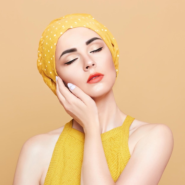 Portrait d'une jeune femme avec un maquillage lumineux et un foulard à la mode sur un fond clair