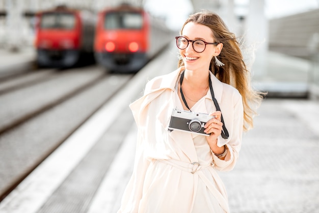 Portrait d'une jeune femme marchant avec un appareil photo à l'extérieur de la gare