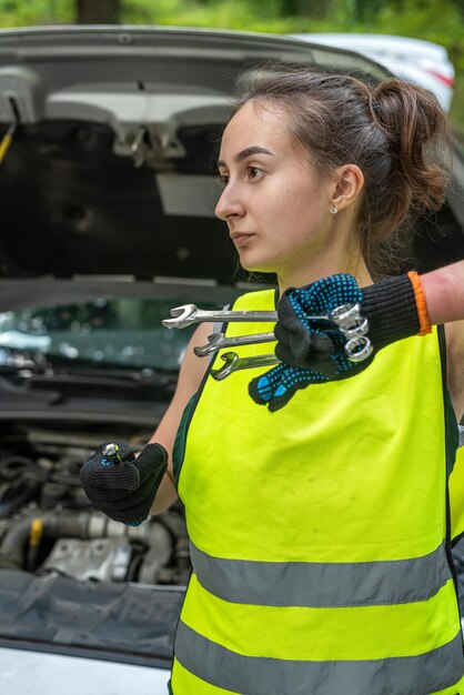 Portrait d'une jeune femme mécanicienne en uniforme près d'une voiture cassée