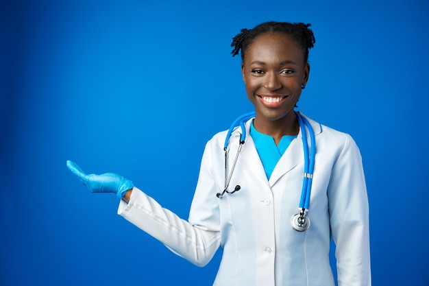 Portrait de jeune femme médecin africaine en studio bleu