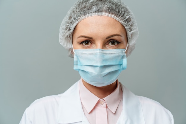 Portrait d'une jeune femme médecin malheureuse dans un masque médical sur fond gris les médecins fatigués