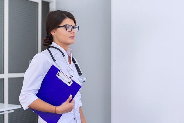 Portrait de jeune femme médecin avec presse-papiers stéthoscope à l'hôpital