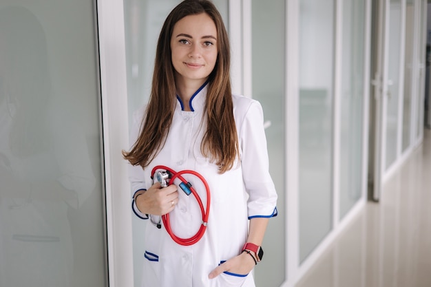 Portrait jeune femme médecin tenant un stéthoscope en mains clinique lumineuse