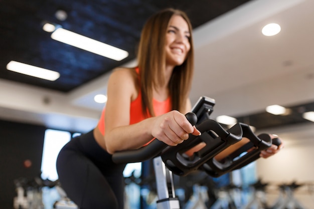 Portrait de jeune femme mince dans une séance de sportwear sur un vélo d'exercice dans la salle de gym. Mode de vie sportif et de bien-être