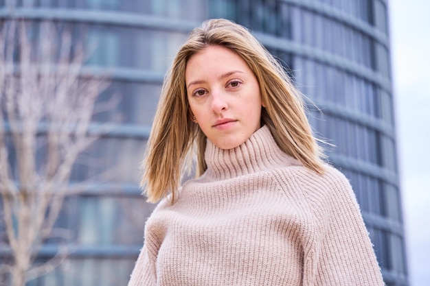 Portrait d'une jeune femme de mode blonde dans un pull à col roulé regardant la caméra