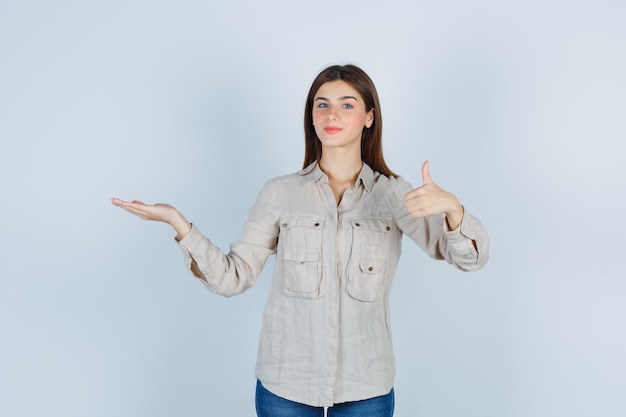 Portrait de jeune femme montrant le pouce vers le haut en tenue décontractée, jeans et à la vue de face satisfaite