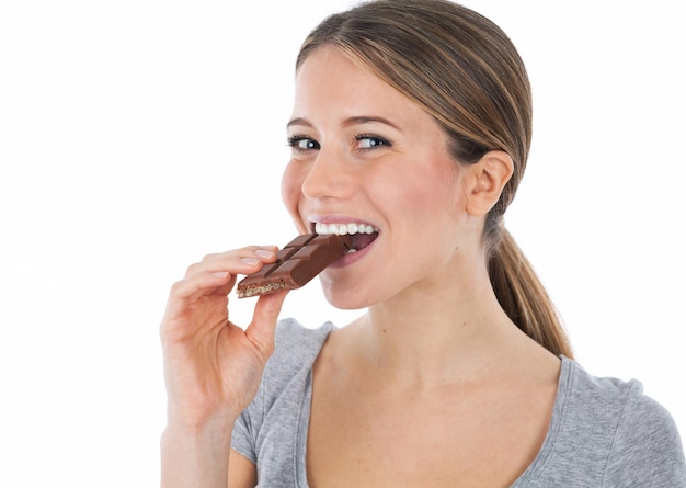 Photo portrait d'une jeune femme mordant une tablette de chocolat isolée sur blanc