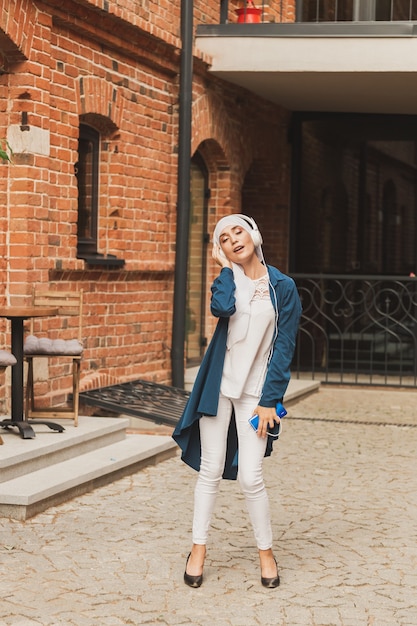 Portrait De Jeune Femme Musulmane Arabe écoutant De La Musique Avec Un Casque Et Dansant. Féminisme, Indépendance De La Femme Et Concept De Loisirs.