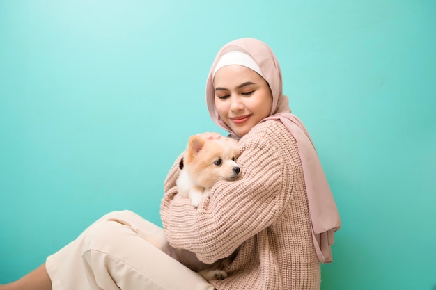 Portrait de jeune femme musulmane embrasse et embrasse son chien sur fond vert