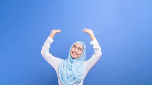 Portrait d'une jeune femme musulmane avec hijab sur bleu