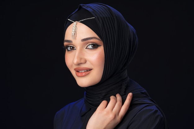 Portrait d'une jeune femme musulmane en hijab sur fond noir