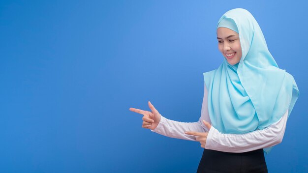 Portrait d'une jeune femme musulmane avec hijab sur mur bleu