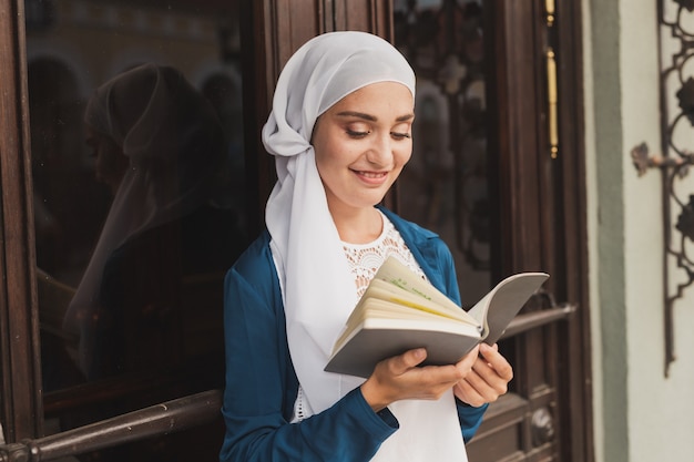 Portrait de jeune femme musulmane portant un livre de lecture hijab à l'extérieur