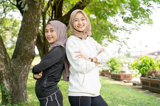 Portrait de jeune femme musulmane sport souriant debout les uns contre les autres en regardant la caméra en plein air