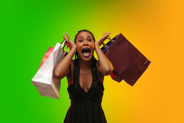 Portrait de jeune femme en néon avec des sacs à provisions, vendredi noir