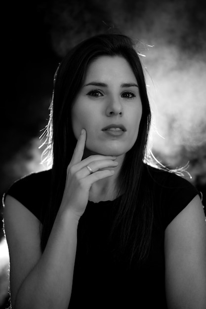 Portrait d'une jeune femme en noir et blanc sur fond noir et fumée