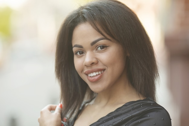 Portrait de jeune femme noire souriante en plein air.