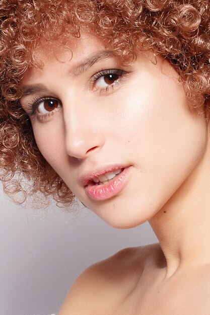 Portrait de jeune femme noire souriante. Portrait d'une belle jeune femme avec une coupe de cheveux afro-américaine et un maquillage glamour. Prise de vue en studio. Jolie fille portant des lunettes.