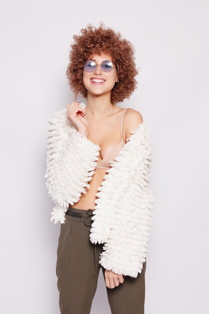 Portrait de jeune femme noire souriante. Portrait d'une belle jeune femme avec une coupe de cheveux afro-américaine et un maquillage glamour. Prise de vue en studio. Jolie fille portant des lunettes