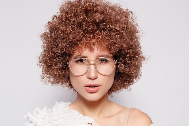 Photo portrait de jeune femme noire souriante. portrait d'une belle jeune femme avec une coupe de cheveux afro-américaine et un maquillage glamour. prise de vue en studio. jolie fille portant des lunettes.