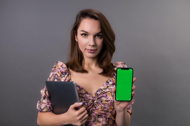 Portrait d'une jeune femme avec un ordinateur portable tenant un téléphone portable avec un écran vert Publicité sur les applications commerciales de gadgets