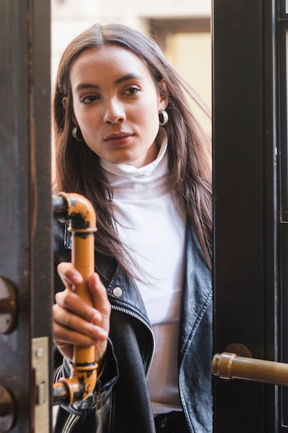 Portrait d&#39;une jeune femme ouvrant la poignée de la porte