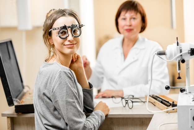 Portrait d'une jeune femme patiente avec un ophtalmologiste senior lors de la consultation au bureau