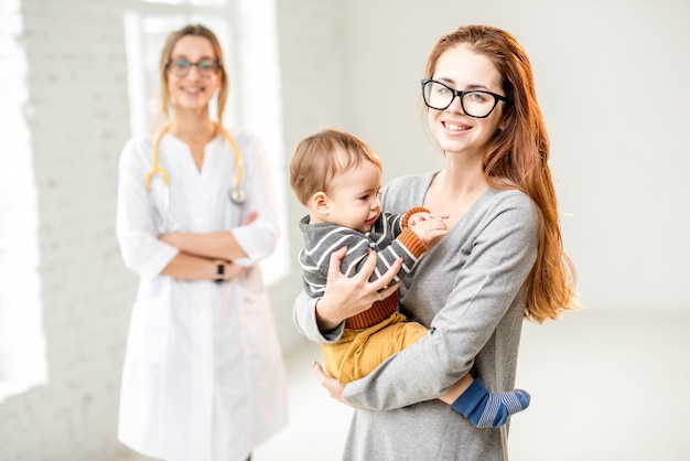 Portrait d'une jeune femme pédiatre avec sa mère et son petit garçon au bureau blanc