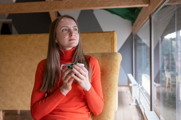 Portrait de jeune femme pencive au café avec une tasse de thé ou de café chaud Fille se repose au café et regarde par la fenêtre