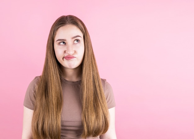 Portrait de jeune femme pensant avec son doigt sur sa tête et regarde sur le côté