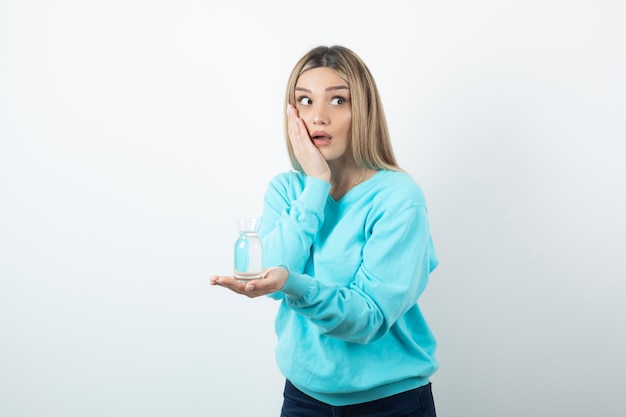 Portrait de jeune femme avec pichet en verre d'eau tenant la main sur la joue