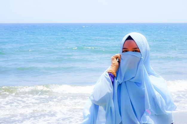 Photo portrait d'une jeune femme portant un hijab debout sur la plage