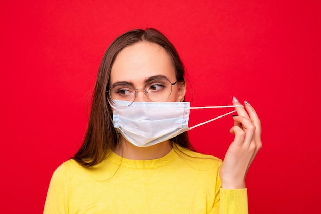 Portrait d'une jeune femme portant des lunettes et un masque de protection sur fond rouge