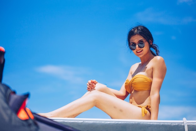 Portrait d'une jeune femme portant des lunettes de soleil assise contre le ciel