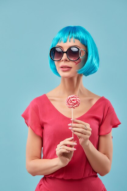 Photo portrait d'une jeune femme portant des lunettes de soleil sur un fond bleu