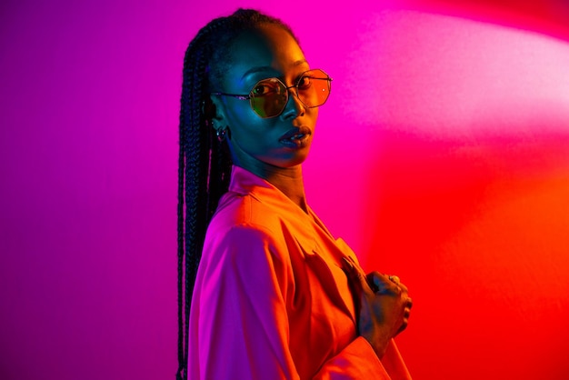 Portrait d'une jeune femme portant des lunettes de soleil sur un fond rose