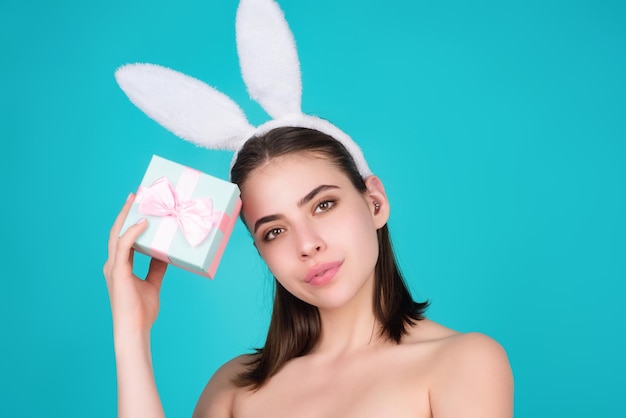 Portrait de jeune femme portant des oreilles de lapin tenant des oeufs de pâques sur fond isolé en studio être